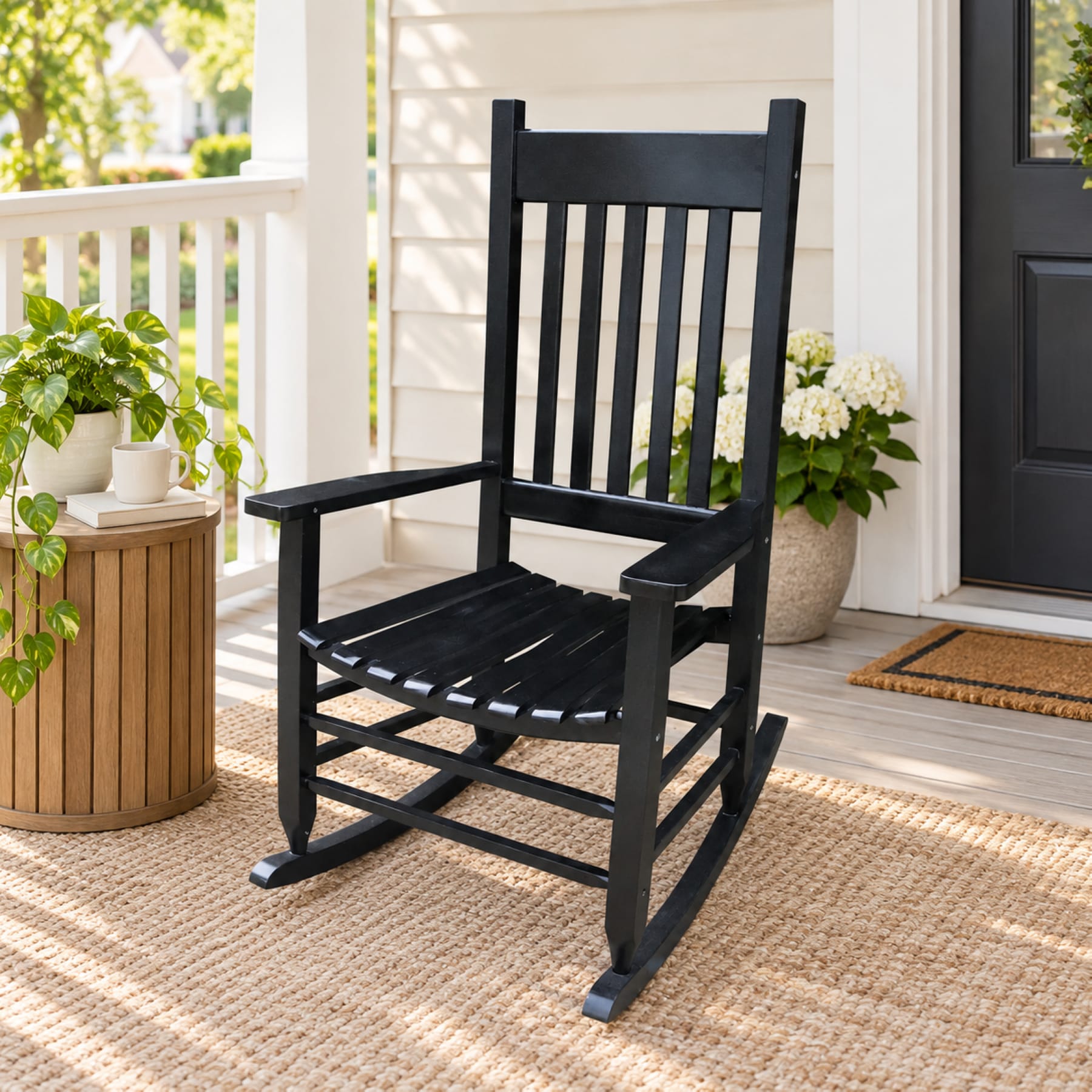 Black solid wood porch rocking chair with tall slatted back and wide armrests on a front porch