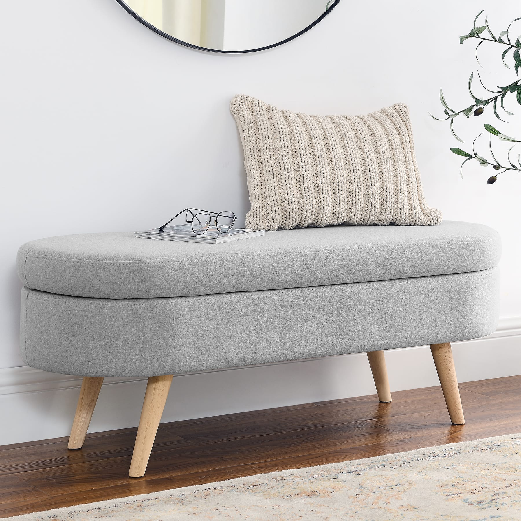 Gray upholstered storage bench placed along a wall in an entryway