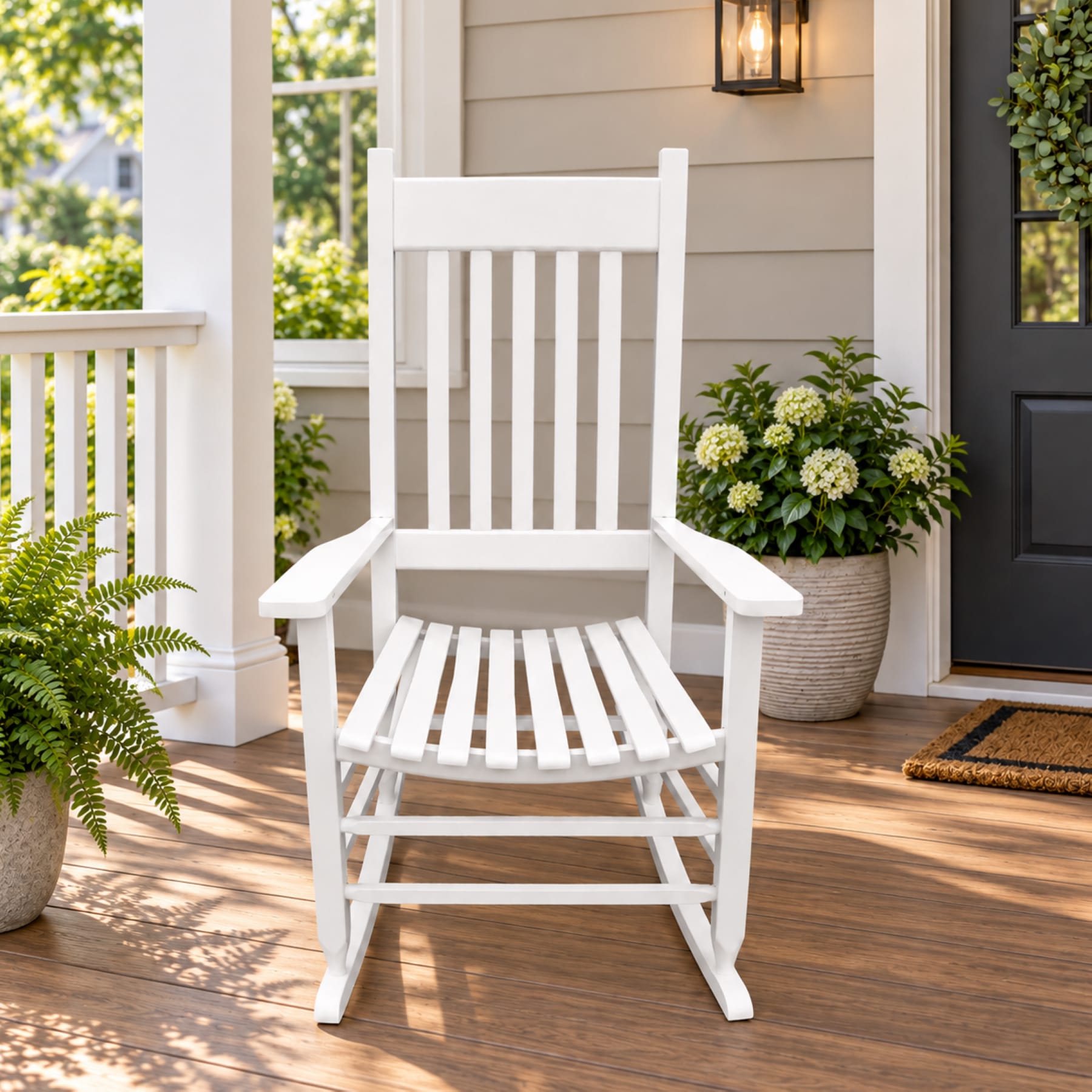 White solid wood porch rocking chair with tall slatted back and wide armrests on a warm front porch
