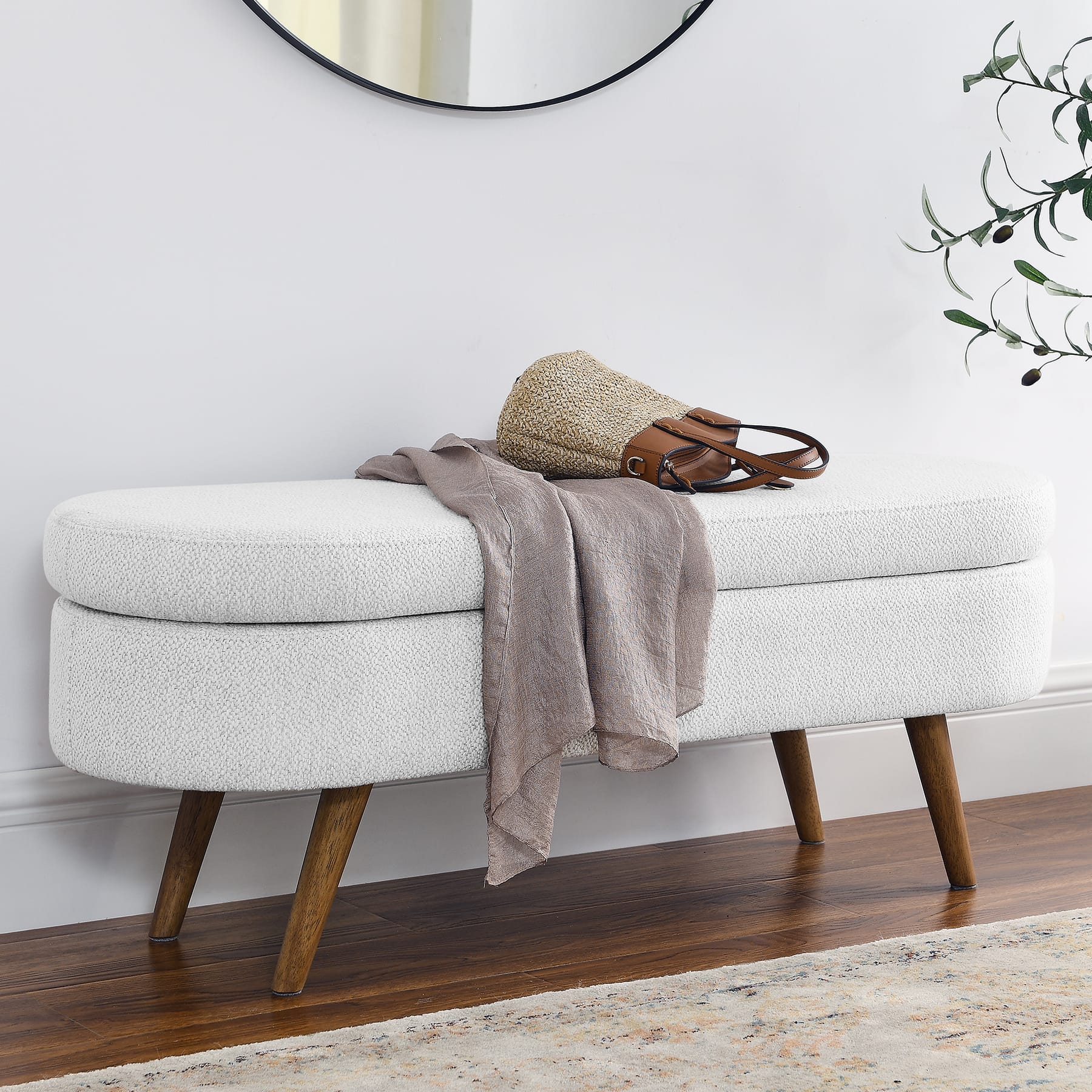 White upholstered storage bench placed along a wall in an entryway