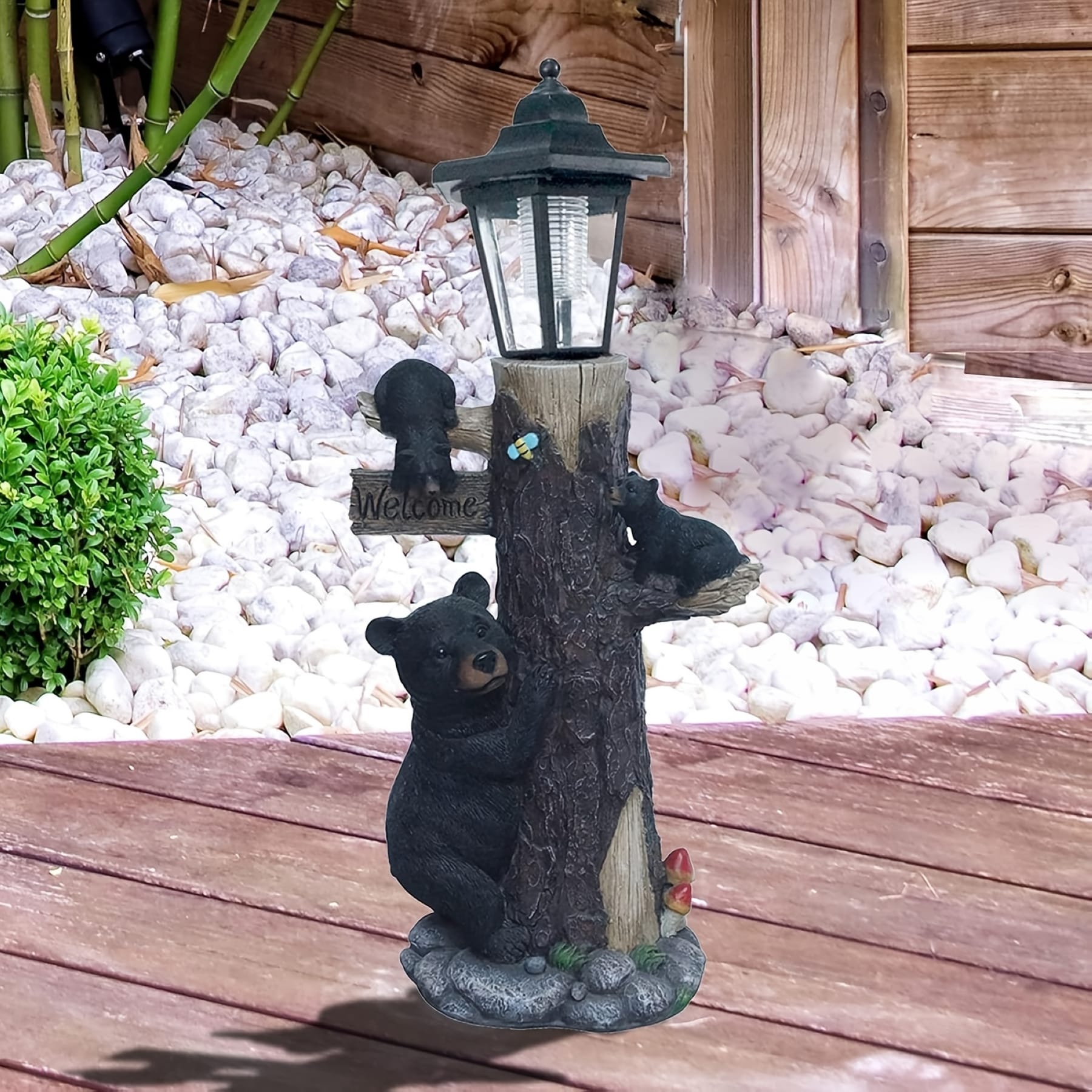 Black bear garden statue with solar lantern and welcome sign beside an outdoor walkway