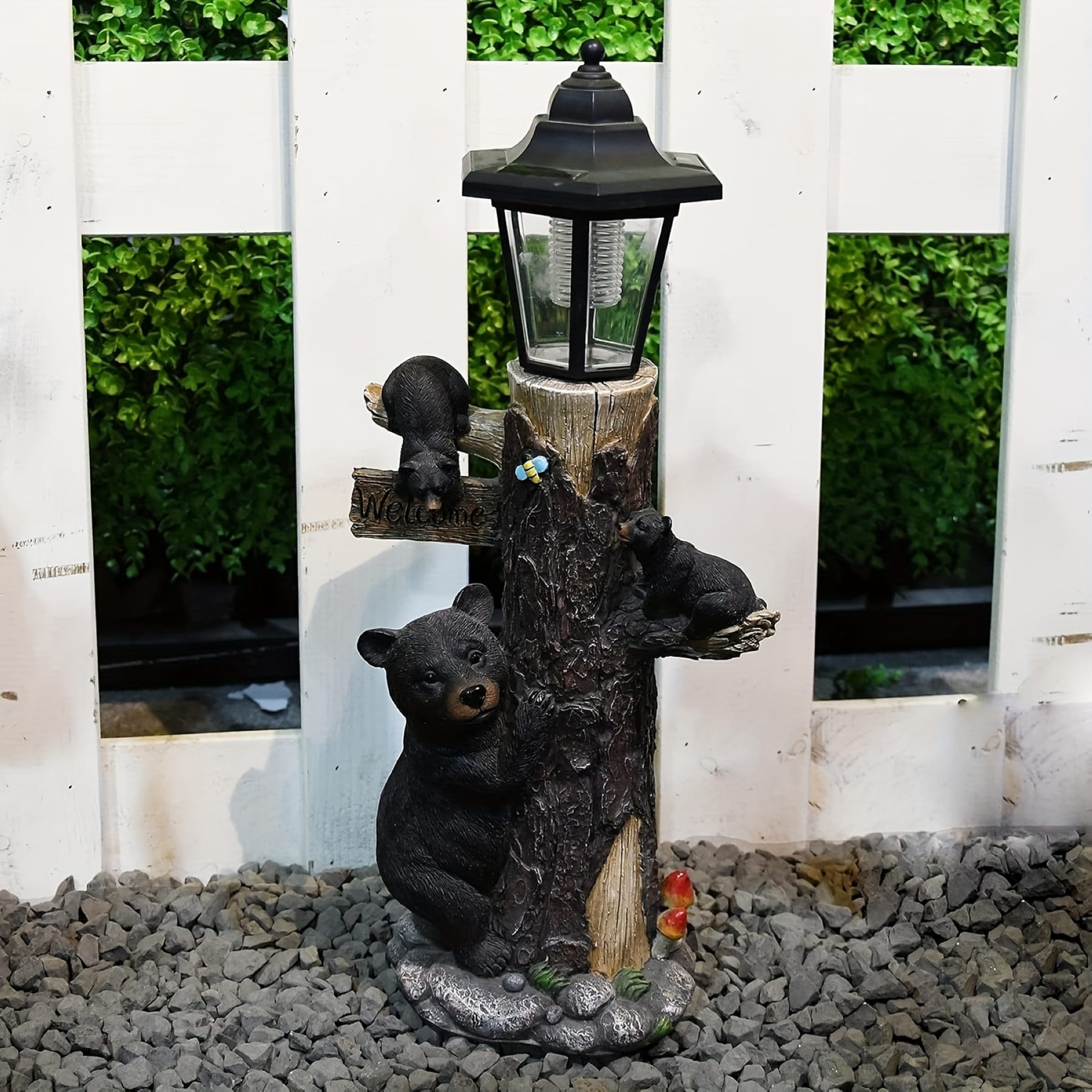 Black bear garden statue with solar lantern and welcome sign displayed outdoors by a white fence