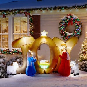 Lighted JOY Christmas inflatable nativity scene with Mary, Joseph, baby Jesus, sheep, and donkey in a snowy front yard